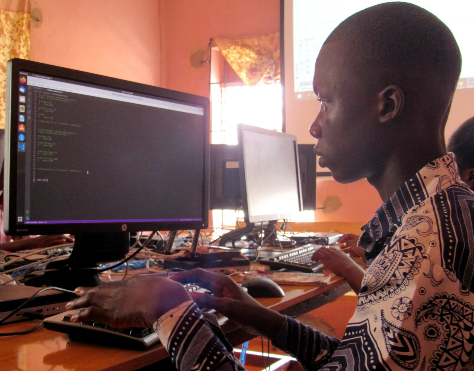 A student concentrating on code at a desktop monitor in MYTECHDEV's Ilesha computer lab.